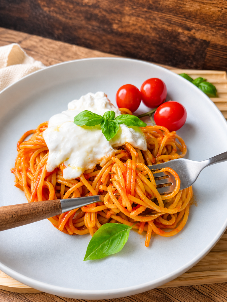 Angeröstete Spaghetti mit Burrata und Basilikum auf der Gabel